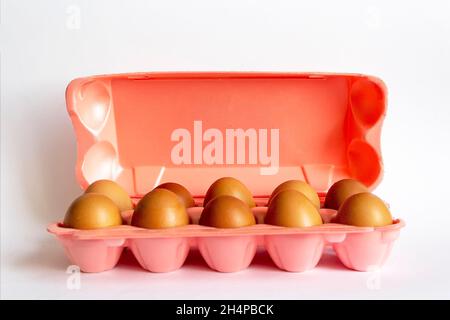Uova di pollo naturali in un cartone rosa su sfondo bianco, Foto Stock