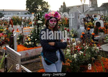 Non esclusiva: CITTÀ DEL MESSICO, MESSICO - 2 NOVEMBRE 2021: I membri della famiglia decorano e illuminano le tombe dei loro cari che riposano nel San Andrés Mixq Foto Stock