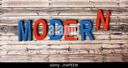 La parola MODERN è composta da lettere multicolore su sfondo di legno, lavoro moderno da casa, freelance. Foto Stock