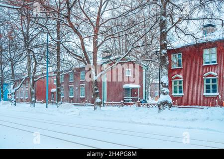 Bellissimo inverno finlandese in campagna. Vecchie case di legno rosso in Finlandia. Vista su una strada innevata dopo la nevicata. Facciate colorate dell'edificio Foto Stock