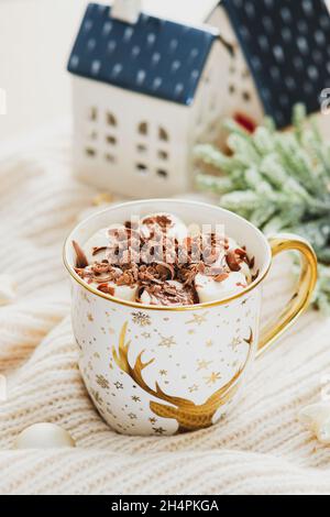 Tazza di caffè con marshmallows e decorazioni natalizie su plaid a maglia. Casa accogliente, Hygge, stile bohémien. Foto Stock