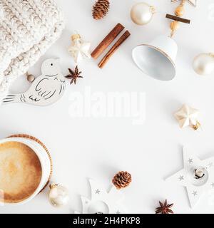 Composizione di Natale. Decorazioni natalizie in legno stile nordico, tazza di caffè, bastoncini di cannella, campane, palline beige sul tavolo bianco vista dall'alto. Igge, b Foto Stock