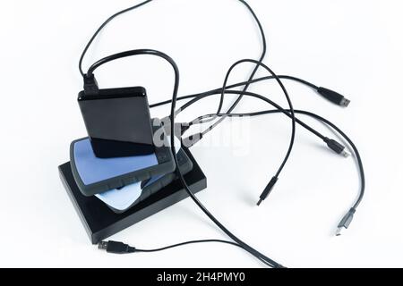 molti dischi rigidi esterni con fili si trovano su uno sfondo bianco. Dischi rigidi isolati Foto Stock