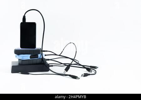 molti dischi rigidi esterni con fili si trovano su uno sfondo bianco. Dischi rigidi isolati Foto Stock