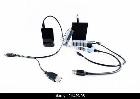 molti dischi rigidi esterni con fili si trovano su uno sfondo bianco. Dischi rigidi isolati Foto Stock