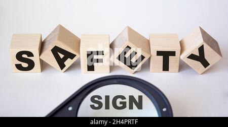 su cubi di legno testo di sicurezza e lente di ingrandimento con segno di testo su sfondo bianco Foto Stock