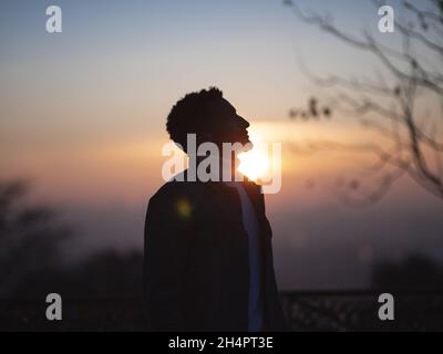 PARIGI, FRANCIA - 02 gennaio 2021: Una silhouette da primo piano di un ragazzo a Montmartre con vista di un bellissimo tramonto Foto Stock