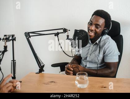 Uomo nero che registra podcast con crop collega Foto Stock
