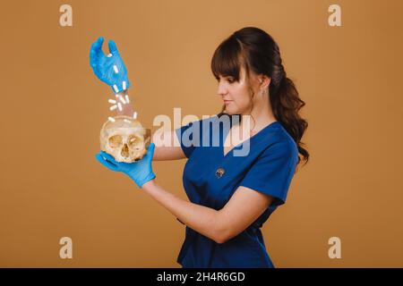 Ragazza intern concentrata piuttosto giovane versando pillole da bottiglia nel suo palmo, vestito in guanti monouso Foto Stock