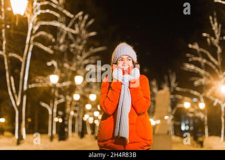 Felice divertente giovane donna con abiti invernali sfondo sera luci città illuminazione. Natale e inverno concetto. Foto Stock