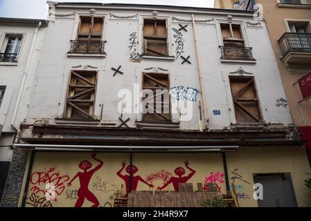 PARIGI, FRANCIA - 1 NOVEMBRE 2021: Vista sulla strada urbana nel 20° arrondissement di vecchia casa abbandonata. Finestre chiuse con tavole di legno. Graffiti