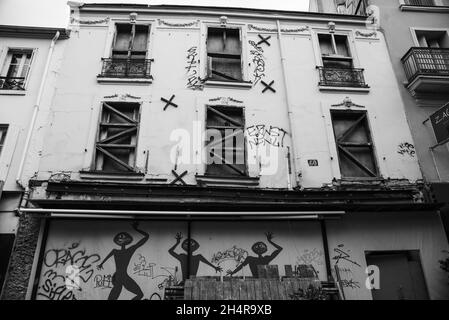 PARIGI, FRANCIA - 1 NOVEMBRE 2021: Vista sulla strada urbana nel 20° arrondissement di vecchia casa abbandonata. Finestre chiuse. Graffiti. Foto in bianco e nero Foto Stock