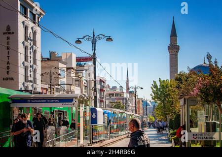 ISTANBUL, TURCHIA. SETTEMBRE 26, 2021. Vista sulla strada della città, piccoli negozi e caffè, la torre della moschea sullo sfondo, luce del giorno Foto Stock