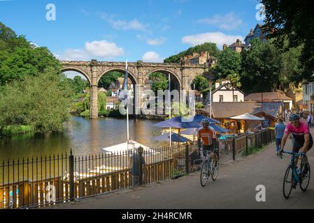 Waterside Knaresborough, vista in estate dei ciclisti che cavalcano le biciclette nella pittoresca zona di Waterside, circondata da caffè, di Knaresborough, North Yorkshire, Inghilterra, Regno Unito Foto Stock