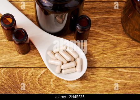 Piatto posare con pillole mediche a base di erbe nel cucchiaio. Assistenza sanitaria e tablet Foto Stock