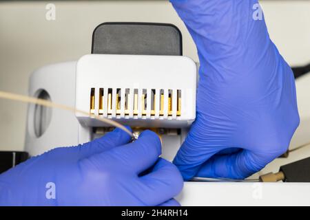 Primo piano l'operatore di laboratorio collega un ago alla sorgente di ioni dello spettrometro di massa. Manutenzione del rilevatore di massa. Analisi LC MS in sala operatoria chimica Foto Stock