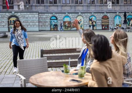 Gruppo di giovani amici multietnici si incontra all'aperto sulla terrazza al caffè dicendo ciao e divertirsi nel centro della città. Foto di alta qualità Foto Stock