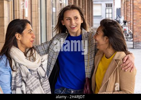 Gruppo multirazziale di ragazze che camminano in città. Sfondo urbano con strada trafficata e marciapiede, amicizia e stile di vita concepts.Group consiste di ragazze indiane, asiatiche e caucasiche. Foto di alta qualità Foto Stock