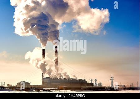 I camini del CHP fumano in una giornata invernale soleggiata Foto Stock