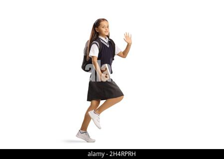 Ragazza in una uniforme scuola salendo a scuola e ondeggiando isolato su sfondo bianco Foto Stock
