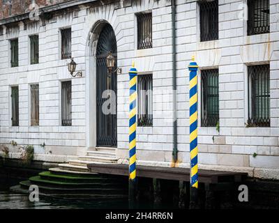 Pali gialli a strisce blu di fronte alla vecchia casa di Venezia (Italia) Foto Stock