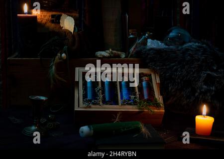 Una scena scura con magici attributi focalizzata su una scatola di legno con bottiglie di vetro riempite di liquido blu e rosso. Foto Stock