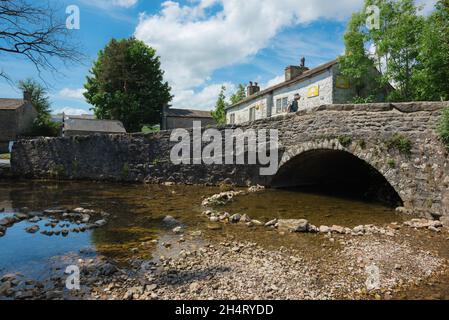 Malham Bridge, vista in estate dello storico ponte che attraversa Malham Beck nel centro del pittoresco villaggio North Yorkshire Dales di Malham, Regno Unito Foto Stock