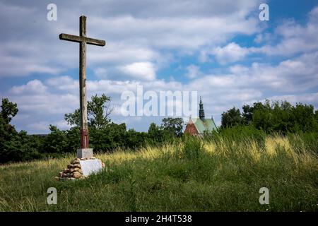 RADOM, POLONIA - 26 luglio 2021: Una croce di legno sulla cima della collina Piotrowka, sulle rovine dell'antico insediamento. Chiesa di San Waclaw sullo sfondo. Foto Stock