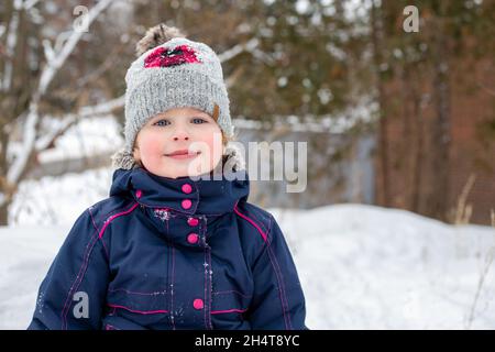 Ritratto di un bambino piccolo che gioca all'aperto in condizioni di neve fredda in inverno Foto Stock