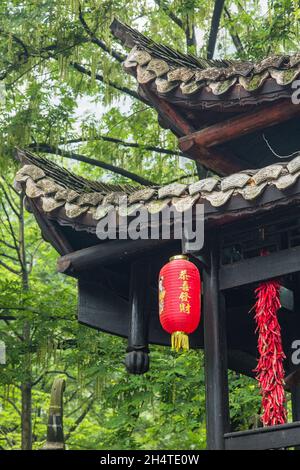 Trefoli di peperoncini rossi e lanterne cinesi in un tradizionale edificio in legno nel Zhangjiajie National Forest Park, Hunan, Cina. Foto Stock