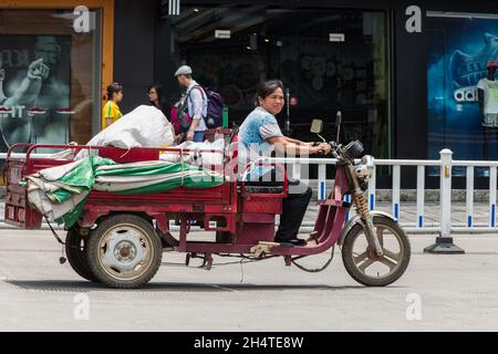 Una donna cinese sul suo veicolo carrello a tre ruote sulla strada a Yangshuo, Cina. Foto Stock