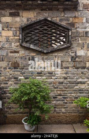 Un disegno in una finestra attraverso un muro di mattoni creato con piastrelle di argilla. Wuzhen, Cina. Foto Stock