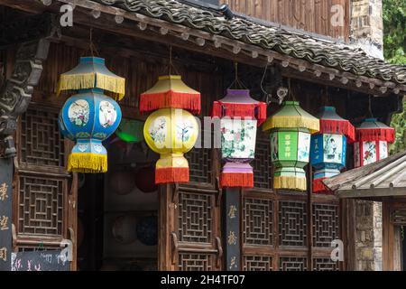 Lanterne cinesi tradizionali sotto le grondaie di un negozio turistico nella città di Wuzhen, Cina. Foto Stock