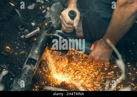 L'operatore taglia il tubo del gas con il macinacaffè, primo piano. Foto Stock
