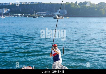 brixham, devon. Maggio 31, 2021. L'uomo mostra alla gente il suo successo di pesca sulla canna da pesca. Giornata felice di pesca sul mare Foto Stock