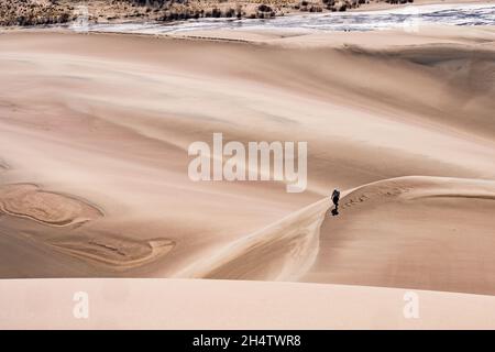 Mosca, CO - 24 aprile 2021: Un escursionista solitario cammina da solo sulle dune nel Parco Nazionale delle Great Sand Dunes Foto Stock