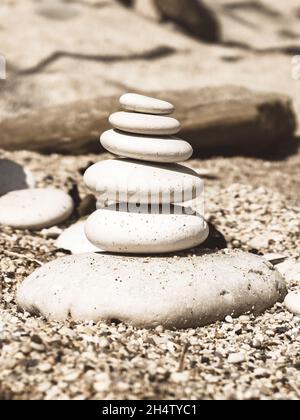 Sephia ciottoli stack su una spiaggia di sabbia, libero copyspace sulla parte superiore Foto Stock