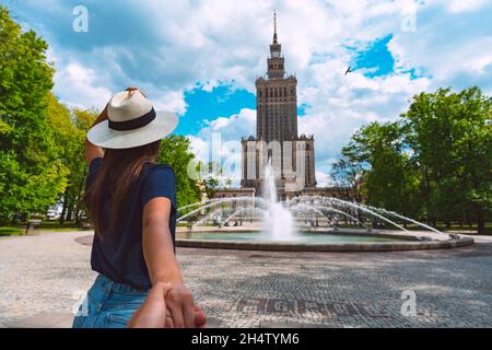 Seguimi. Giovane donna turistica che tiene il suo ragazzo a mano nella città di Varsavia Foto Stock