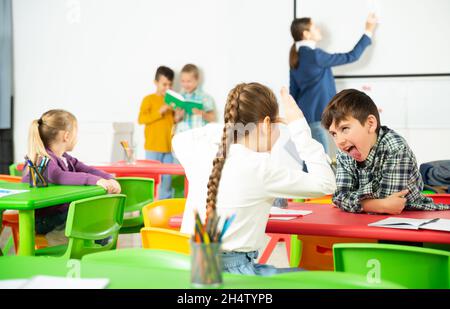 Felice di chattering alunni seduti a lezione a scuola elementare Foto Stock