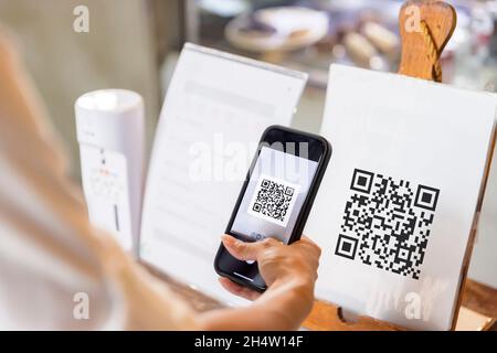 Mano di donna che utilizza lo smartphone per eseguire la scansione del codice QR. Foto Stock