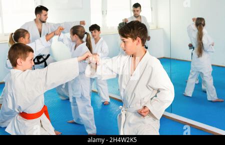 Adolescenti che praticano nuove mosse di karate in coppia in classe Foto Stock