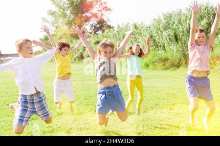 I bambini saltano e alzano le mani Foto Stock