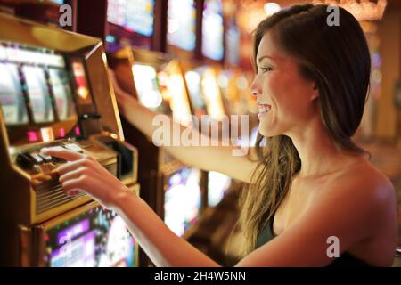 Donna asiatica gioco d'azzardo in casinò giocare su slot machine spendere soldi. Giocatore additto a spin macchina. Ragazza asiatica giocatore, vita notturna. Las Foto Stock