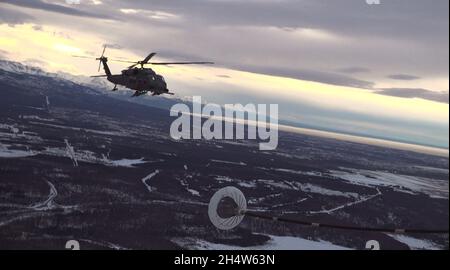 I membri del 210th e 211th Rescue Squadrons, Alaska National Guard, praticano il rifornimento aereo in un elicottero HH-60G Pave Hawk sopra Alaska 21 gennaio 2021. Questa pratica ha aiutato i membri dell'unità a eseguire future missioni di salvataggio. (STATI UNITI Foto della Guardia Nazionale dell'aria dello staff Sgt. Kelly Willett/rilasciato). Foto Stock