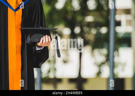 Primo piano Graduate tenendo un cappello. Formazione di successo di concetto in università con spazio di copia. Foto Stock