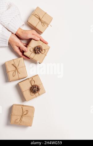 Le mani femminili tengono un regalo in un imballaggio ecologico di carta. Regalo per Natale o Capodanno fai da te Foto Stock