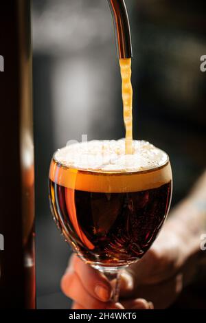 versare la birra alla spina artigianale in un bicchiere Foto Stock