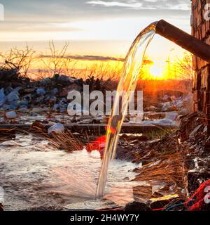 L'acqua fuoriesce da un vecchio tubo arrugginito Foto Stock