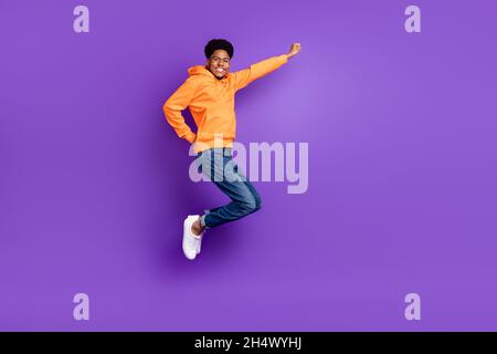 Foto a tutta lunghezza di giovane brunetto capelli pelle scura uomo salto in su sogno spazio vuoto volare isolato su sfondo di colore viola Foto Stock