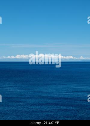 Blu Ionio e vista panoramica verticale in Grecia. Giorno luminoso con panoramiche nuvole bianche su una superficie d'acqua blu profonda increspata Foto Stock